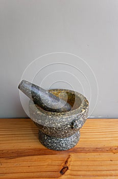 Stone Mortar & Pestle on the wood table gray wall. important tool for making Thai food