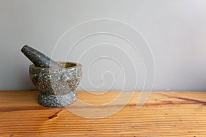 Stone Mortar & Pestle on a wood table gray wall. important tool for making Thai food