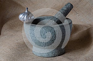 Stone mortar with a silver head of garlic