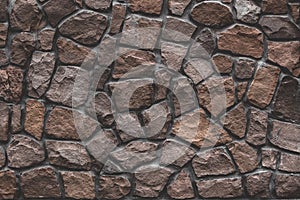 Stone mosaic, brown masonry. Old stone wall surface, brown stone texture, background. Rocks, bricks building`s facade. Pattern of