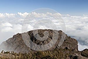 Stone mountain rock face above a sea of clouds