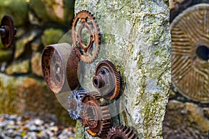 A stone in the park is inlaid with a pile of rusty gear sculptures