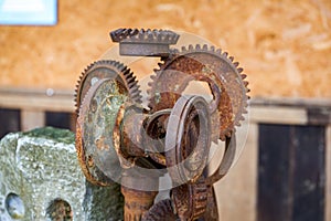 A stone in the park is inlaid with a pile of rusty gear sculptures