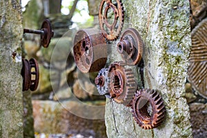 A stone in the park is inlaid with a pile of rusty gear sculptures