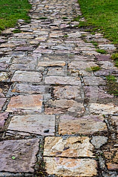 Stone path lined with cobblestones among the grass