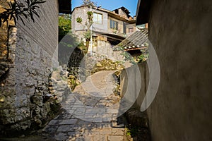 Stone path between old houses on slope in sunny morning