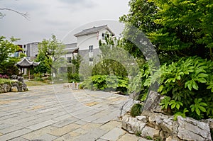 Stone path with tile-roofed buildings in distance on cloudy day