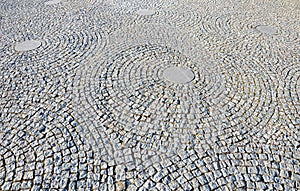 Stone paving in the square folded into circles with a larger tile in the middle of gray granite