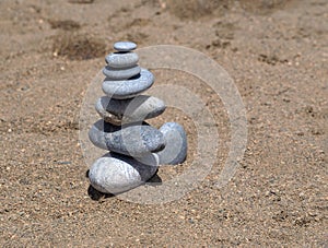 A stone pyramid on fine sand made of flat and round stones.