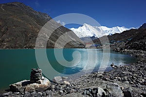 Stone pyramid next to sacred Gokyo lake with view of Gokyo village and Cho Oyu mountain. Hiking in Nepal