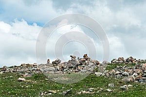 Stone pyramids of cobblestones on top of mountain under thick clouds overlooking valley