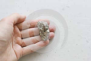 Stone pyrite lies in the hand. Beautiful iron in the hand of natural pyrite. On a white background. Golden and golden stone or