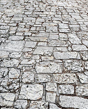 Stone road close up. Old pavement of granite. Grey cobblestone sidewalk. Mock up or vintage grunge texture.