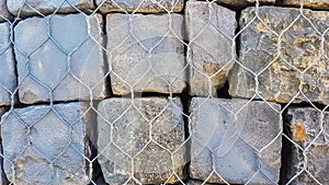 Stone Rock Bricks Behind Metal Fence Wall Wallpaper Background Texture.Close Up of Massive Stone Rocks for Construction