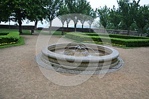 Stone sandstone circular fountain in the park. built of sandstone filled with water. lined with a light threshing gravel road with