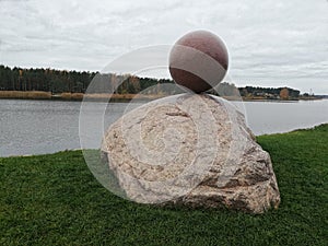 Stone sculpture ball sphere nex to river