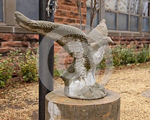 Stone sculpture of an eagle with outstretched wings on a concrete pedestal at the base of a flagpole in Edmond, Oklahoma.