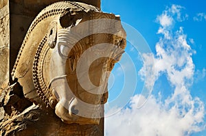 Stone sculpture of a horse in Persepolis against a blue sky with clouds. The Victory symbol of the ancient Achaemenid Kingdom.