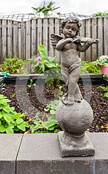 Stone sculpture of a little angel holding a violin instrument garden decoration