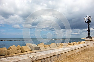 Stone seaside with iron street lantern on cloudy day. Adriatic seascape. Italian panoramic coastline. Italian south background.