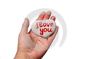 stone in shape of heart with inscription written by hand I love you on female palm on white background