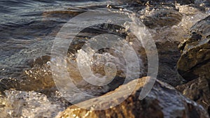 Stone shore of the lake. Waves wash over the pebbles. Lake at sunset