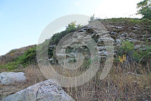 Stone slope overgrown with grass. Hill of old stone.