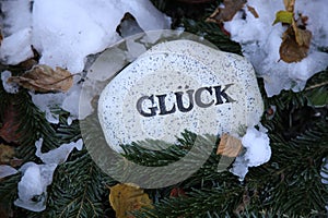 Stone on snowy tree branches with an inscription in German Gluck meaning Luck photo