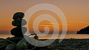 Stone stack fireplace with rope on beach at sunrise