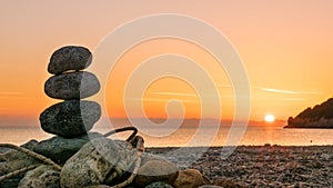 Stone stack fireplace with rope on beach at sunrise