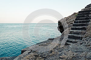Stone stairs on the rock to the blue sea