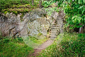 Stone stairway disappears into a lush green forest. Odderoya, Kristiansand, Norway