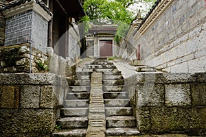 Stone stairway on slope before gates of buildings in cloudy spring after rain