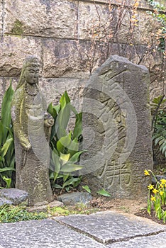 Stone statue of amitabha buddha and his name engraved in japanese ideographs on a stone monument in the Choanji temple in Tokyo