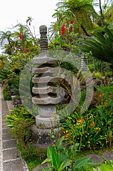 Stone statue in a beautiful Monte Palace tropical garden in Madeira, surrounded by green vegetation