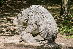 Stone statue of a brown bear in a park on a sunny day