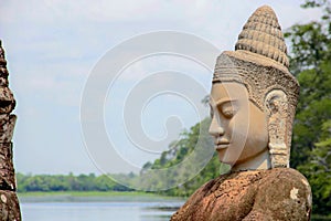 Stone statue Deva at the south gate of Angkor Thom, Angkor Wat. Overlooking the Moat