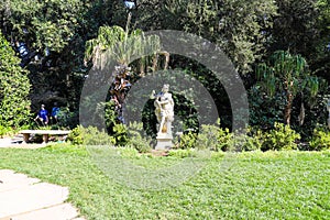 A stone statue in the garden of a roman soldier surrounded by lush green trees