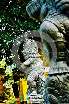 Stone statue of god guarding sacred temple with colorful traditional cloting