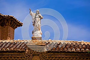 Stone statue of Jesus on a tile roof in Granada