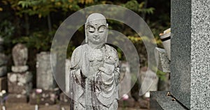 Stone statue in traditional Japanese graveyard with peace, calm and quiet garden with memorial tombstone. Buddha