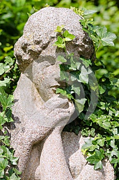 Stone statue of woman overgrown by ivy