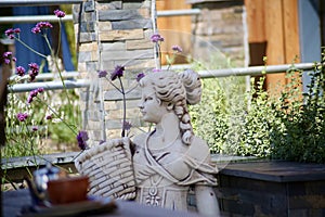 Stone statue of a woman and verbena flowers