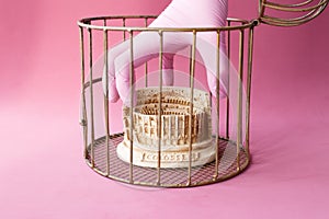 Stone statuette of the Coliseum building in the city of Rome in Italy, enclosed in a golden cage. Hands of doctor in medical