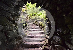 Stone steps leading upwards as seen through a secret exit in a stone grotto