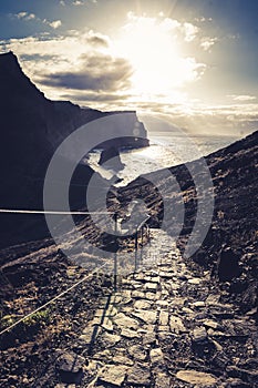 Stone steps in a rough rocky cliff landscape on a hiking trail going Down to the sea during sunset