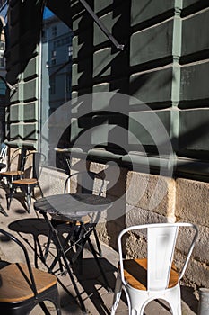 Stone street cafe - metal chairs, tables. Sunny day.
