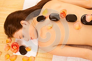 Stone therapy. Woman getting a hot stone massage at spa salon