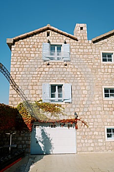 Stone three-story apartment building entwined with green and red ivy