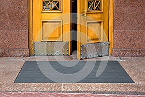 Stone threshold with black rubber foot mat at opening yellow door.